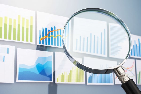 Many graphs and magnifying glass on gray background